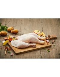 Zwei frisch zubereitete Bauernhähnchenschenkel auf einem Holzbrett, umgeben von Kartoffeln, Karotten, Zwiebeln und Knoblauch. Bauernhähnchen kaufen bei Metzgerei Fritsch.