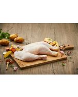 Zwei frisch zubereitete Bauernhähnchenschenkel auf einem Holzbrett, umgeben von Kartoffeln, Karotten, Zwiebeln und Knoblauch. Bauernhähnchen kaufen bei Metzgerei Fritsch.