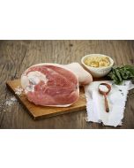 Gepökelte Surhaxe von Metzgerei Fritsch auf einem Holzbrett, serviert mit Salz aus Holz und einem Schälchen Kartoffelsalat. Das zarte Fleischstück ist umgeben von Kräutern und einem Stofftuch, ideal für festliche Gerichte.